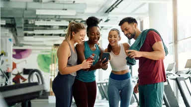 4 people looking at a phone at a gym